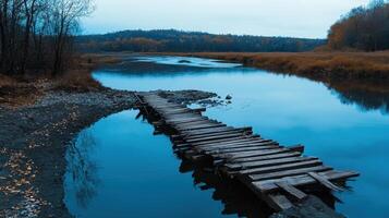 A wooden bridge crosses over a river in the middle of a forest photo