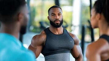 A man with a beard and muscles is standing in front of a group of people photo