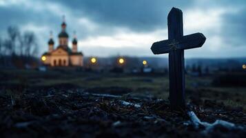 A small wooden cross is standing in a field next to a church photo