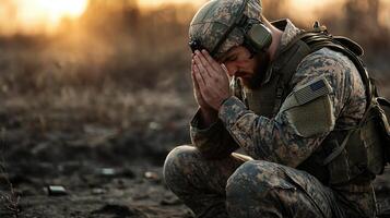 A soldier is kneeling in the desert praying photo