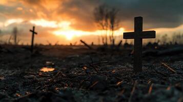 A cross is standing in the middle of a field with a sunset in the background photo
