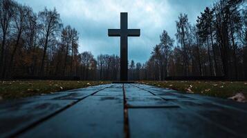 A black cross is in the middle of a path in a forest photo