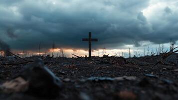 A cross is standing in a field of dead grass and rocks photo