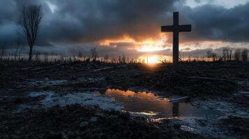 A cross is standing in a field with a sunset in the background photo