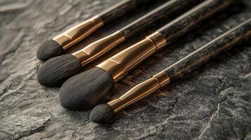 Several high-quality makeup brushes with sleek handles rest on a textured stone surface, showcasing their soft bristles and elegant design, ideal for beauty routines photo