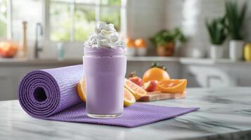 Smoothie made with vibrant purple ingredients topped with whipped cream sits on a yoga mat. Fresh fruits surround the smoothie in a warm, inviting kitchen atmosphere photo