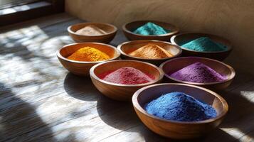 Colorful bowls of colored powder on a wooden table photo