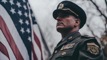 A man in uniform stands in front of an american flag photo
