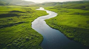 River in the middle of green grassland with mountains in the background photo