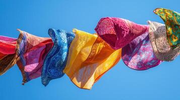Brightly colored scarves are hanging in the air, gently swaying with the wind against a brilliant blue sky during a lively festival. The atmosphere is joyful and full of energy photo