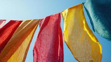 Banners of bright colors including red, yellow, and green sway gently in the wind against a backdrop of a clear and sunny sky, creating a vibrant atmosphere photo