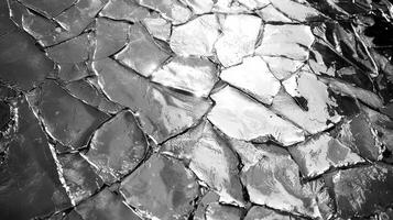 Textured surface displays an intricate pattern of cracks, reflecting light in various shades of gray. The interplay of light and shadow creates a visually striking monochrome effect photo