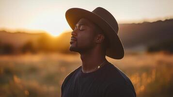 A man wearing a hat in a field at sunset photo