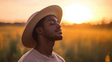 A man wearing a hat in a field at sunset photo
