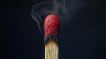 A matchstick with a red tip and smoke coming out photo
