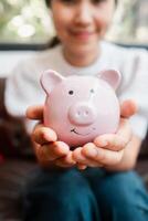 Close-up of a woman holding a pink piggy bank, representing savings and financial planning. photo