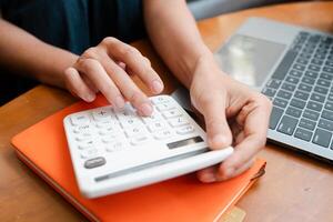 Close-up of hands using a calculator on a desk with a laptop and notebook, ideal for financial planning and budgeting concepts. photo