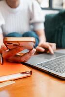 Person multitasking with smartphone and laptop, focusing on technology and productivity in a cozy home setting. photo