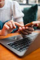 A person interacts with a smartphone and laptop, highlighting technology use in a comfortable home setting. photo