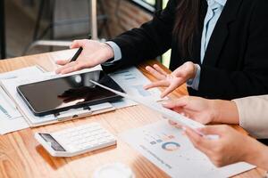 Professionals discussing financial charts and data using a tablet in a modern office environment. photo