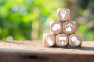 Wooden blocks with user experience icons symbolizing feedback, navigation, and interaction, set against a blurred natural background. photo