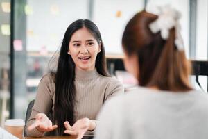 Smiling young woman having a conversation with a colleague in a modern office environment. photo