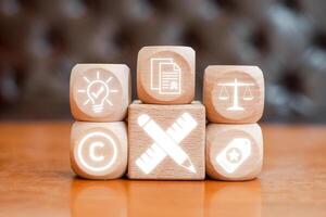 Wooden blocks with icons symbolizing intellectual property, copyright, innovation, and legal protection. photo