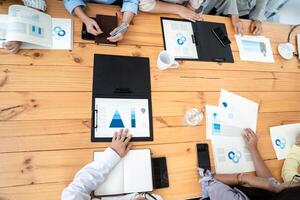 Employees Meeting in conference room. There are triangular diagrams, graphs, and related data set aside on a long brown wooden plate photo