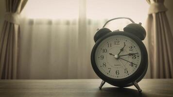 4K Timelapse of Black alarm clock in house with curtain background and soft sunlight, vintage style. Time moves quickly, working hours, and management time concept. video