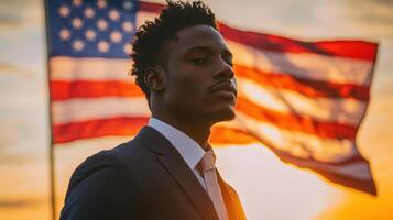 A confident man in formal attire poses with an American flag waving behind him as the sun sets. The warm colors of twilight enhance the proud atmosphere of the moment photo