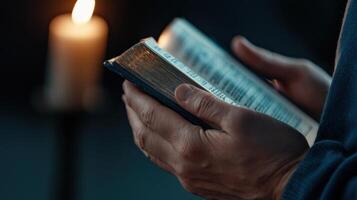 A person holding a bible and a candle photo