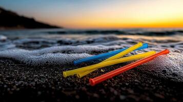 Three colorful straws laying on the beach at sunset photo
