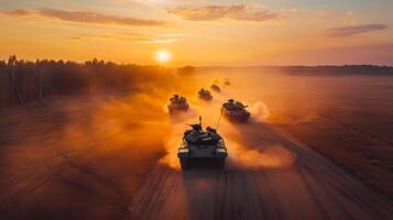 Multiple military tanks advance through a dusty landscape under a vibrant sunset, creating a dramatic backdrop for a training exercise in a wooded environment. photo