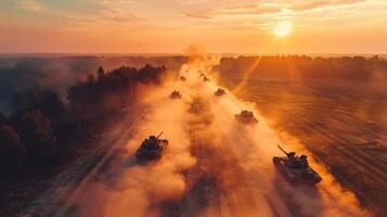 Sunset casts an orange glow as military tanks move through a foggy field, creating a dramatic display of power and precision during a tactical maneuver. photo