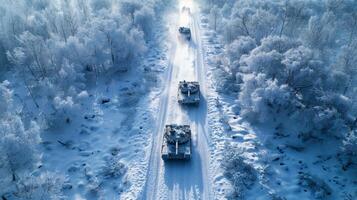 Tanks are moving in formation along a snowy path surrounded by frosted trees in a remote winter landscape. The serene yet powerful scene captures the essence of military maneuvers. photo