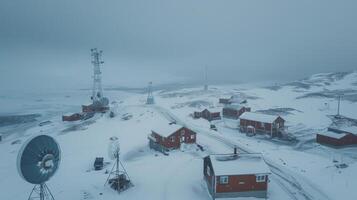 Snow blankets a remote Arctic settlement filled with communication equipment and small structures, depicting a cold winter day under a gray sky and low visibility. photo