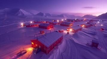 The twilight sky casts a soft glow over a remote research settlement surrounded by snow covered mountains. Warm lights illuminate red cabins, creating a serene winter atmosphere. photo