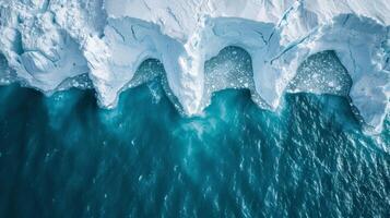 Unique ice formations are visible near the water's edge, where the bright turquoise ocean meets the snowy shoreline on a crisp winter day. photo