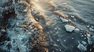 Crystal clear water glistens under the warm glow of the setting sun as waves interact with floating ice chunks, creating a mesmerizing arctic scene that captures nature's beauty. photo