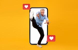 A man enthusiastically interacts with a smartphone, using social media to express love and excitement. The background is vibrant yellow, emphasizing the theme of connection and technology. photo