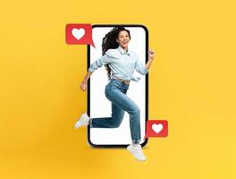 A lively woman is joyfully leaping out of a smartphone, surrounded by red heart icons, symbolizing connection and affection. The bright yellow background enhances the cheerful vibe. photo