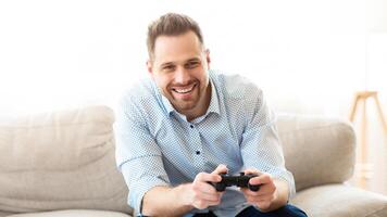 Weekend Time. Smiling man using console sitting on comfortable sofa, copy space photo