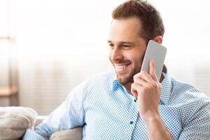 Pleasant Talk. Closeup portrait of smiling guy making phone call spending time at home, copy space photo