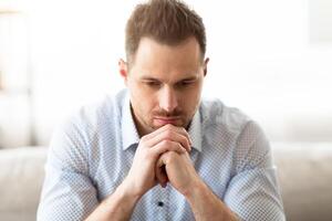 Close up frontal portrait of handsome pensive bearded man thinking about something, copy space photo
