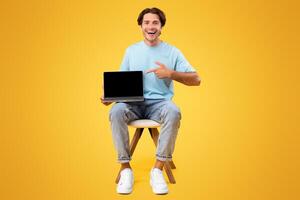 Check This Great Website. Portrait of happy guy holding pc in hand and pointing finger at laptop with black blank screen, showing device with empty free space for mock up, presenting notebook photo