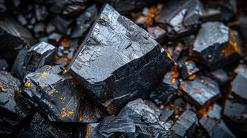 Black crystals are clustered together, showcasing sharp edges and reflective surfaces enhanced by patches of orange. The intricate textures reveal the natural beauty of these minerals. photo