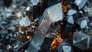 A captivating array of black and clear crystals with sharp edges and glittering surfaces, arranged closely together, illuminated by a warm glow revealing their unique textures and formations. photo