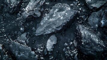 Close up of charcoal pieces displaying a rich texture and dark sheen. The varied shapes create a natural and striking pattern under soft lighting. photo