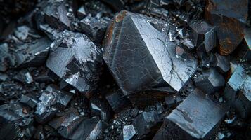 Large black crystals are clustered together, showcasing unique geometric shapes and surfaces that reflect light, emphasizing their natural beauty in a mineral rich area. photo