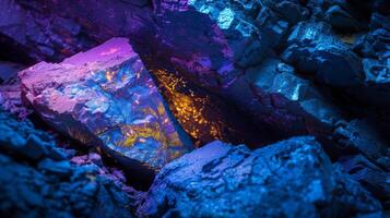 A crystal formation sits amid rough rocks, glowing with vibrant colors. The light creates a captivating contrast with the dark surroundings, highlighting the textures and patterns. photo